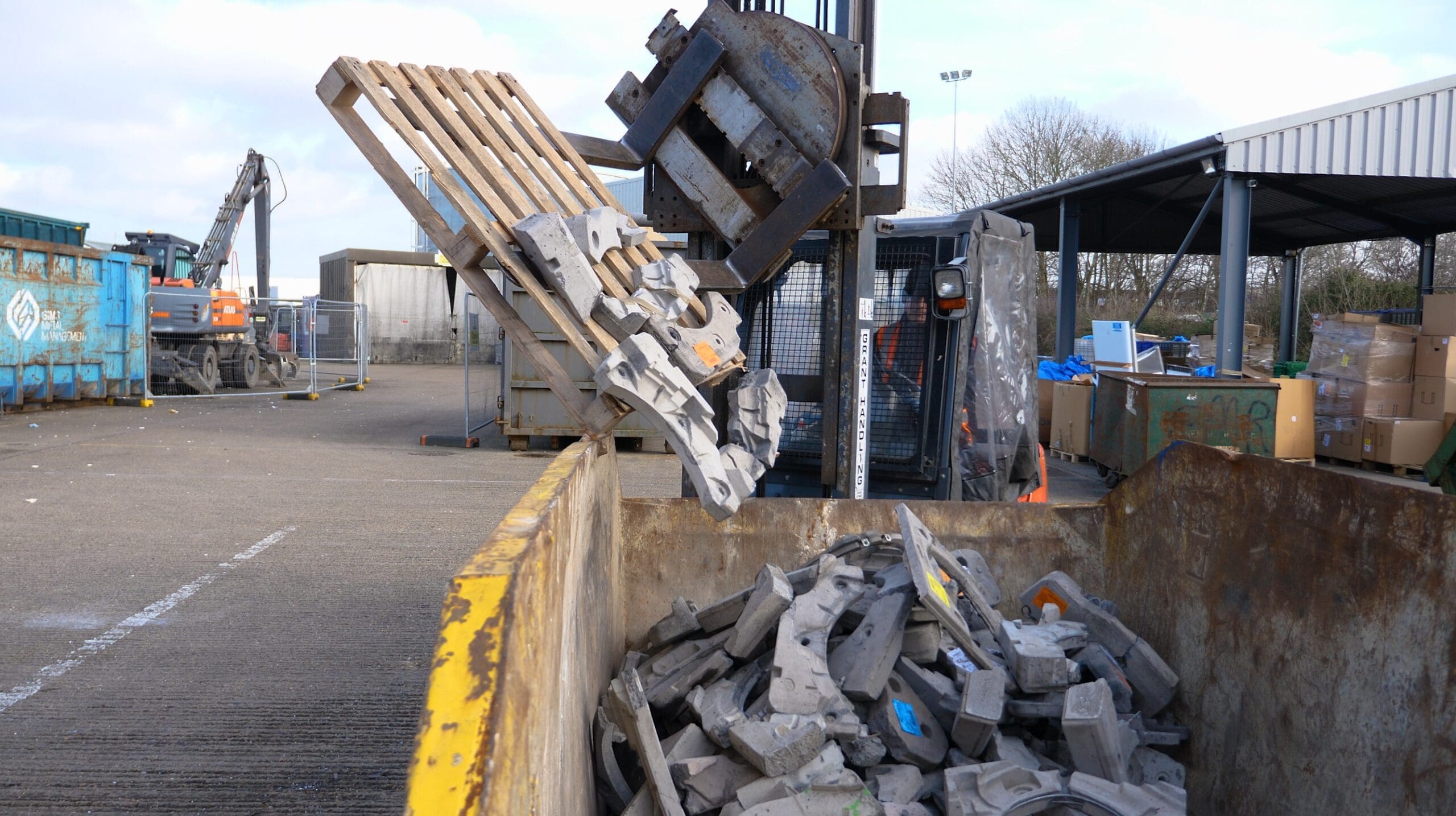 Rotating forklift putting waste in a skip at Whirlpool Axil.