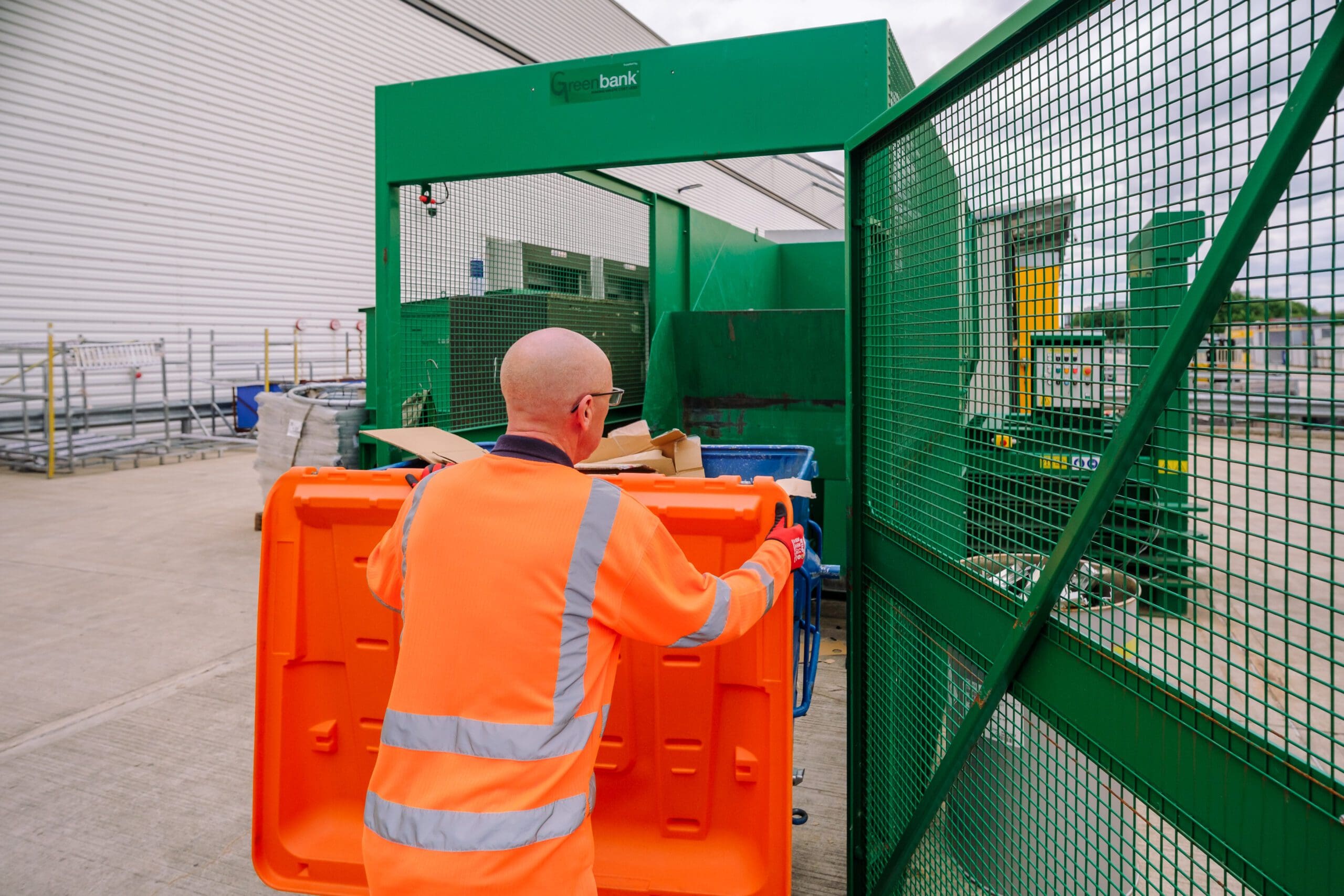 An Axil employee putting cardboard into a cardboard baler