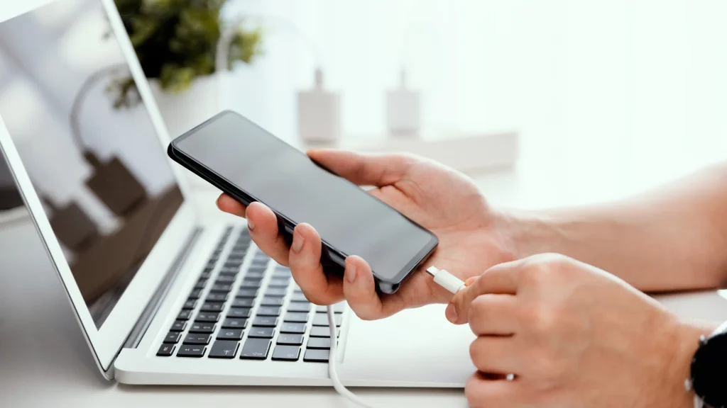 Man charging smart phone in the office, using charger